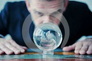 Businessman looking at glass ball on table