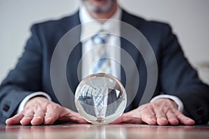 Businessman looking at glass ball on table