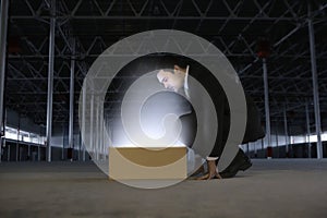 Businessman Looking At Glowing Box In Empty Warehouse