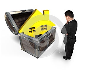 Businessman looking at golden house in treasure chest