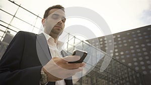 Businessman looking at his phone and waiting for someone outside the building