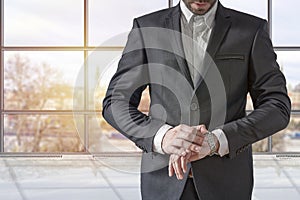 Businessman looking at his watch on his hand, watching the time in the office