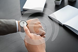 Businessman looking at his watch indoors. Time management concept