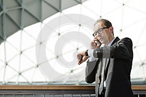 Businessman looking at his watch and talking on phone