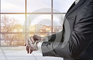 Businessman looking at his watch and watching the time in the office