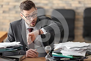 Businessman looking at his wristwatch at table in office. Time management concept