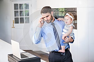 Businessman looking in laptop while carrying daughter