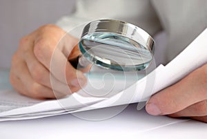 Businessman looking through a magnifying glass photo
