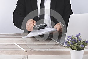 Businessman looking through a magnifying glass for documents