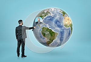 Businessman looking through magnifying glass on Earth