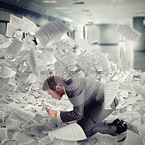 Businessman looking with magnifying glass in the middle of a flood of sheets