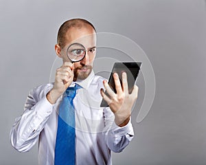 Businessman looking through a magnifying glass on a Tablet PC