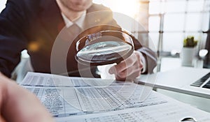 Businessman looking through a magnifying glass to document