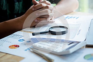 Businessman looking through a magnifying glass to documents. Business assessment and audit. Magnifying glass on a financial report