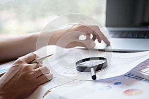 Businessman looking through a magnifying glass to documents. Business assessment and audit. Magnifying glass on a financial report