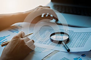 Businessman looking through a magnifying glass to documents. Business assessment and audit. Magnifying glass on a financial report