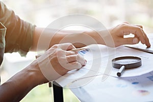 Businessman looking through a magnifying glass to documents. Business assessment and audit. Magnifying glass on a financial report