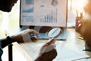 Businessman looking through a magnifying glass to documents. Business assessment and audit. Magnifying glass on a financial report