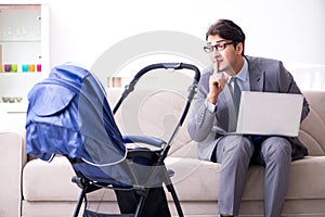 The businessman looking after newborn baby at home and teleworking