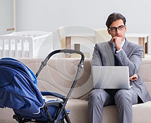 Businessman looking after newborn baby at home and teleworking