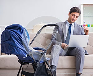 Businessman looking after newborn baby at home and teleworking