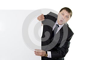 Businessman looking out from behind a blank
