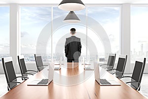 Businessman looking out the window in modern conference room wit