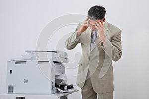 Businessman Looking At Paper Stuck In Printer