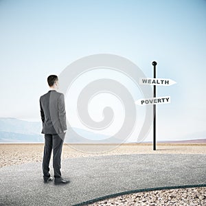 Businessman looking on poverty and wealth sign post