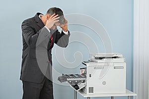 Businessman Looking At Printer Machine At Office
