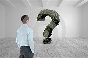 Businessman looking at question mark made of plants