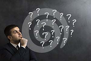 Businessman looking question marks on the blackboard