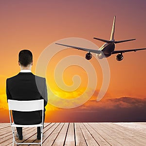 Businessman looking at sunset and airplane