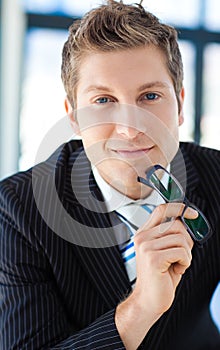 Businessman looking to the camera holding glasses