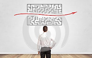 Businessman looking to a maze on a wall