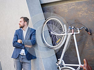 Businessman looking to the side, next to the bike is lifted on his hind legs