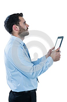 Businessman looking up while holding a digital tablet