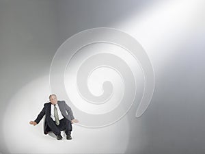 Businessman Looking Up At Source Of Spotlight