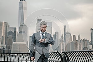 Businessman looking on watch to managing time for organization of business. Business man on cityscape in NYC. Business