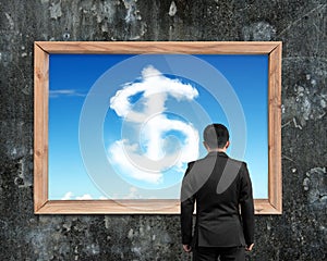 Businessman looking at wooden frame white dollar sign shape clou