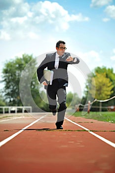 Businessman looking wrist watch watch running on athletic track in stress