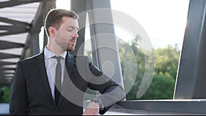 A businessman looks at his wristwatch, smiling, waiting for the arrival of a friend, colleague or meeting.