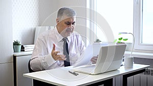 Businessman looks through reports with dissatisfaction