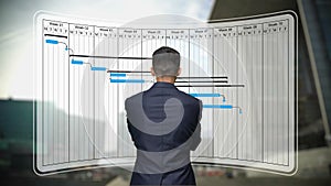 Businessman looks to Gantt chart, project schedule harmonogram work processes