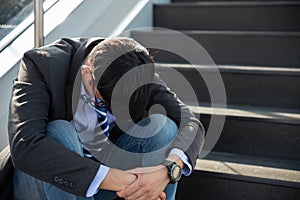 Businessman lost in depression crying sitting on ground street stairs suffering emotional pain sadness. Unemployed jobless people