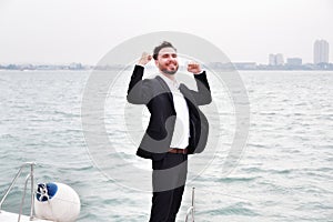 Businessman on luxury yacht with smartphone, handsome man wearing white shirt and suit on boat