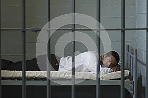 Businessman Lying On Bed In Prison Cell