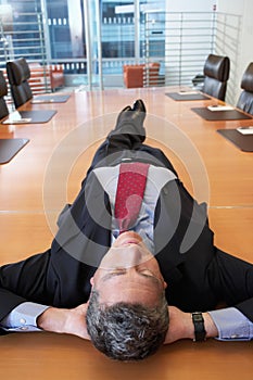 Businessman Lying On Conference Table