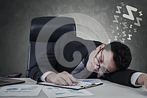 Businessman lying on desk with closed eyes