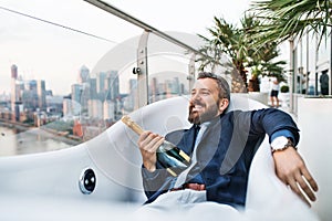 Businessman lying in empty hot tub, London view panorama in the background.